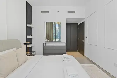 a white bedroom with a white bed and a window at Golden Stays - Luxury 1BR Apartment I Cinema Access I Pool & Gym in Dubai
