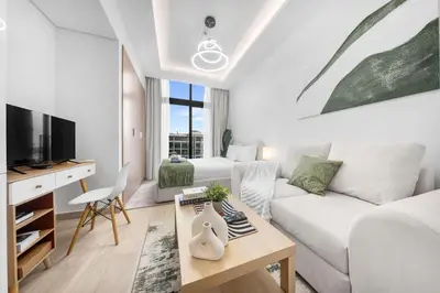 a living room with a white couch and a tv at StayShort - Studio Apartment at Azizi Riviera with Balcony in Dubai