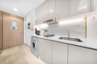a kitchen with a sink and a washing machine at StayShort - Studio Apartment at Azizi Riviera with Balcony in Dubai