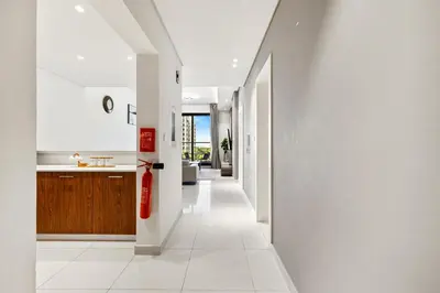 a kitchen with white walls and a white tile hallway at BLVD - Stylish Stay with Relaxing Balcony View in Dubai