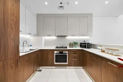 a kitchen with white appliances and wooden cabinets at BLVD - Stylish Stay with Relaxing Balcony View in Dubai