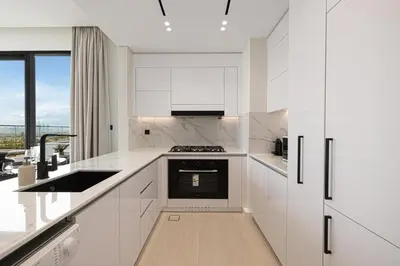 a white kitchen with a sink and a stove at GuestReady | 2 BR | Luxury Apt with Private Pool in Dubai