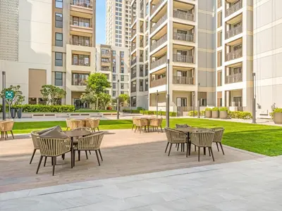 a patio with tables and chairs in front of a building at Stylish Dubai Stay 1BR, Lagoon, Pool, Gym in Dubai