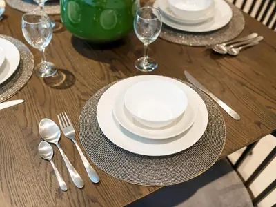 a wooden table with white plates and silverware on it at Stylish Dubai Stay 1BR, Lagoon, Pool, Gym in Dubai