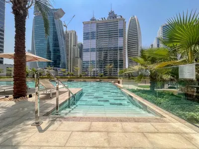 a swimming pool with palm trees and buildings at GuestReady - 1BR l Canal View in Business Bay in Dubai