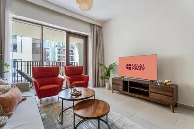a living room with red chairs and a flat screen tv at GuestReady - 1BR | Creek Beach Getaway in Dubai