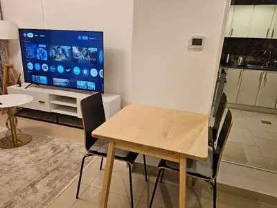 a dining room with a table and a large screen tv at Marina View Apartment Near JBR Beach & Marina Mall in Dubai