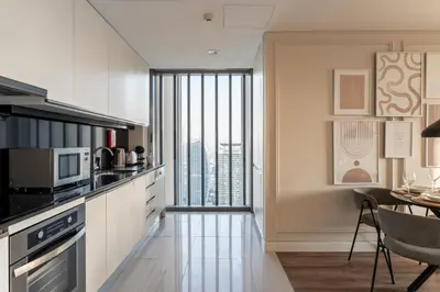 a kitchen with white cabinets and a dining room with a table at GuestReady - 1BR | High-Floor Skyline Elegance in Dubai