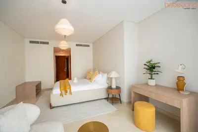 a bedroom with a white bed and a table at 3BR Skyline Burj Panorama with Infinity Pool Vibes in Dubai