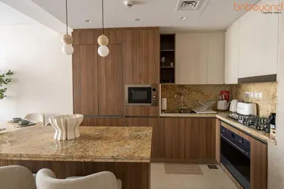 a kitchen with wooden cabinets and a counter top at 3BR Skyline Burj Panorama with Infinity Pool Vibes in Dubai