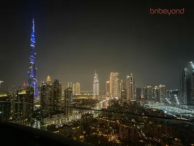 a city skyline at night with a blue lit up building at 3BR Skyline Burj Panorama with Infinity Pool Vibes in Dubai