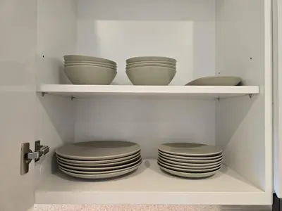 a bunch of bowls and plates on shelves in a kitchen at Full Burj Khalifa & Fountain Views - Luxury 2BR in Downtown Dubai in Dubai