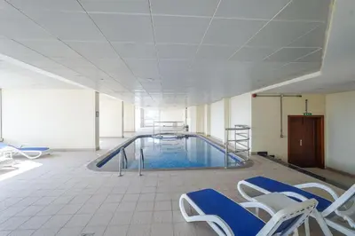 a pool in a room with chairs and a swimming pool at ZenStay - Charming Studio in JLT, near JBR &Marina in Dubai