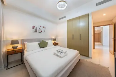 a bedroom with a large white bed and a table at Burj Royale Luxury 3BR Apartment in Dubai