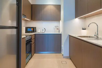 a kitchen with wooden cabinets and a sink at 1BR with Full burj khalifa and fountain view in Dubai