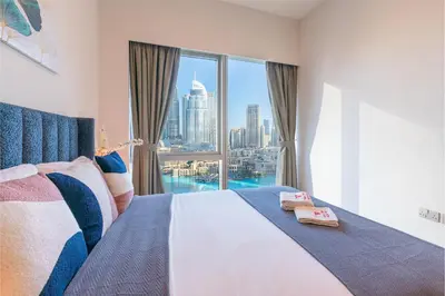a bedroom with a bed with a view of the city at 1BR with Full burj khalifa and fountain view in Dubai