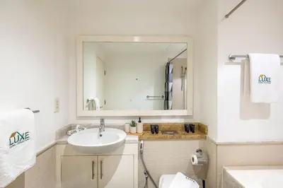 a white bathroom with a sink and a mirror at South Ridge By Luxe Living - Full Burj Khalifa View in Dubai
