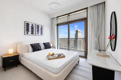 a bedroom with a white bed and a large window at BLVD-Manhattan Vibes 4BR High Floor Creek in Dubai