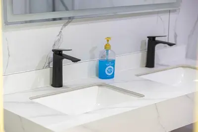 a bathroom sink with two faucets and a bottle of soap at Luxury 3 BHK in Dubai Marina DEC 1402 T2 in Dubai