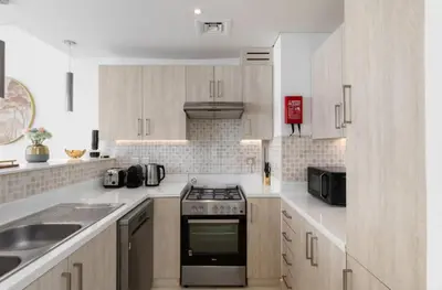 a kitchen with white cabinets and a stove top oven at Beach Access, Skyline Views, 2 Bedroom and Hall in Dubai