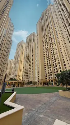 a group of tall buildings with a green field in front at 2BR Beach Side Lux JBR Retreat - Luxury Pool Bahar in Dubai