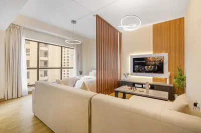 a living room with a large couch and a bedroom at 2BR Beach Side Lux JBR Retreat - Luxury Pool Bahar in Dubai