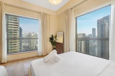 a bedroom with a white bed and large windows at 2BR Beach Side Lux JBR Retreat - Luxury Pool Bahar in Dubai