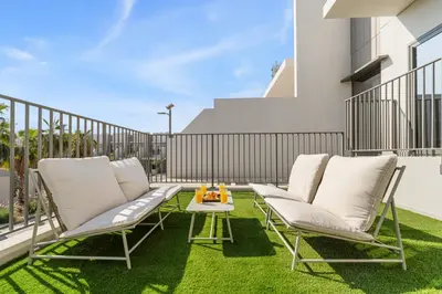 a patio with white chairs and a table on grass at Family 4BR Villa | PS5 & Garden | New Community in Dubai