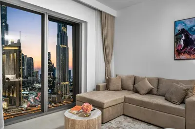 a living room with a couch and a large window at 2BR Burj View - Downtown Views 2 - Dubai Mall Access in Dubai