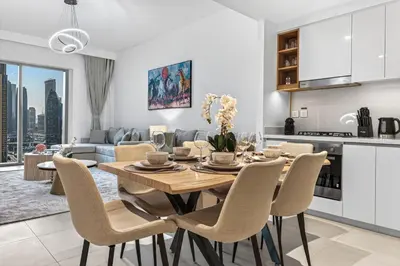 a kitchen and living room with a wooden table and chairs at 2BR Burj View - Downtown Views 2 - Dubai Mall Access in Dubai