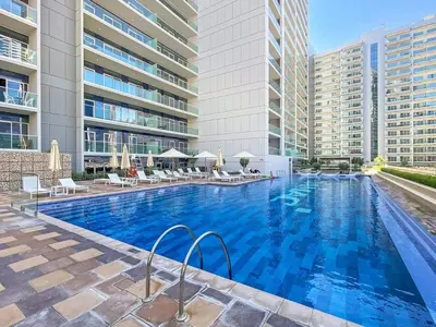a large swimming pool with chairs and a building at Modern 1-Bedroom Luxury Stay with Lake View in Reva, Business Bay in Dubai