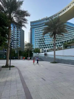 people walking in a plaza with palm trees and a building at Studio in Seven Palm in Dubai