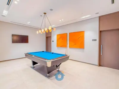 a pool table in a room with orange paintings at Wake up To Burj Khalifa Views Luxury 2 BR LikeHome in Dubai