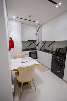 a small kitchen with a table and a washing machine at Luxury Studio with Private Jacuzzi at Trillionaire, Business Bay in Dubai