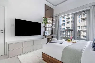 a white bedroom with a flat screen tv on a wall at Frank Porter - Blvd Central in Dubai