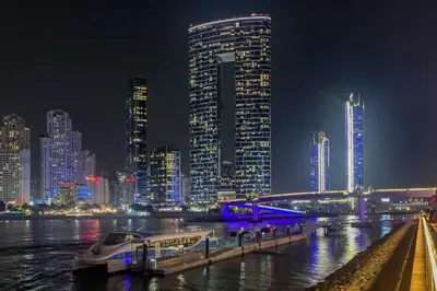 a boat docked at a dock in a city at night at Frank Porter - Studio One Tower in Dubai