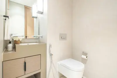 a white bathroom with a toilet and a sink at Frank Porter - Address Beach Resort Tower in Dubai