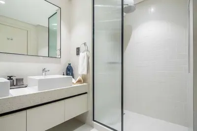 a white bathroom with a sink and a shower at Frank Porter - Marina Vista Tower 2 in Dubai