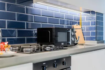 a kitchen with blue tiles on the wall and a microwave at TRPS - MAG 318, Business Bay - Walk to Dubai Mall, Furnished Apt, Premium Amenities in Dubai