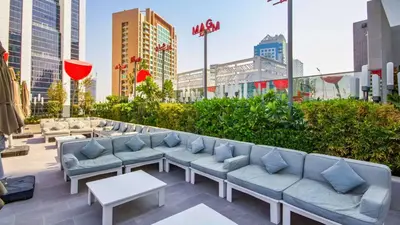 a rooftop patio with couches and tables in a city at TRPS - MAG 318, Business Bay - Walk to Dubai Mall, Furnished Apt, Premium Amenities in Dubai