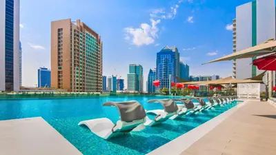 a row of swivelling chairs in a pool with a city skyline at TRPS - MAG 318, Business Bay - Walk to Dubai Mall, Furnished Apt, Premium Amenities in Dubai