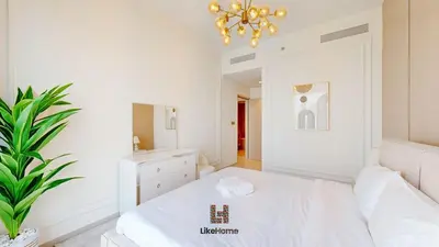 a white bedroom with a bed and a chandelier at Wake Up to Burj Khalifa Views Next to Dubai Mall Luxury 2BR Downtown Like Home in Dubai
