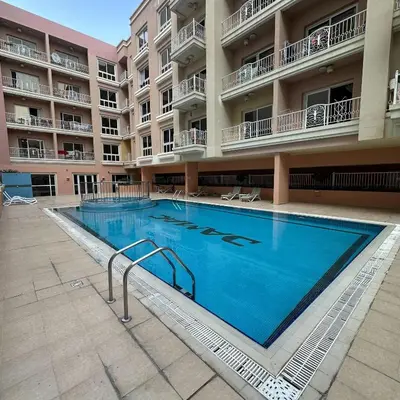 a large swimming pool in front of a building at Stylish Studio Apartment in JVC in Dubai