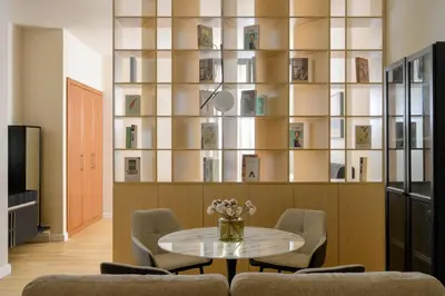 a living room with a table and chairs and a book shelf at Stylish Studio Apartment in JVC in Dubai