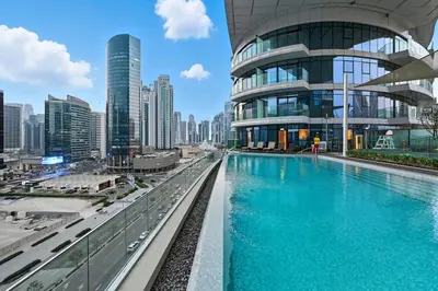 a building with a swimming pool in front of a city at Stunning 1BR Luxury Downtown Burj View Balcony in Dubai