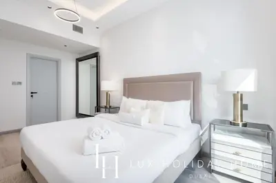a white bedroom with a large bed and a nightstand at LUX The Dubai Marina View Suite 3 in Dubai