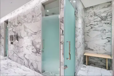 a bathroom with a glass shower with a marble wall at Crest haven suite in Dubai