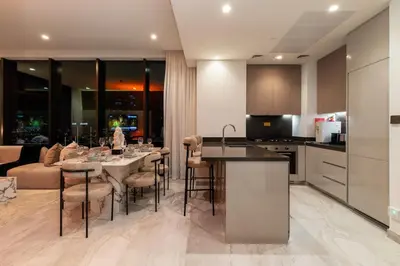 a kitchen and living room with a table and chairs at 3BR Ultra Luxury Waterfront Panoramic Views with Pool, Gym, Jacuzzi -10 mins to Burj Khalifa in Dubai