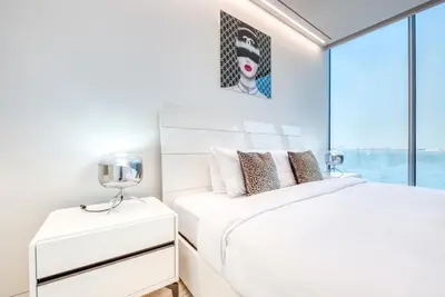 a white bedroom with a bed and a window at Luxury Apartment at Muraba Residence in Dubai