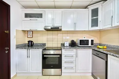 a white kitchen with white cabinets and appliances at Family Stay JBR 3BR and maids room l Walk to Beach l Marina in Dubai